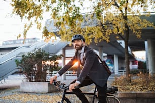 日没時に市内の仕事から家に帰る電動自転車を持つ流行に敏感な実業家。スペースをコピーします。