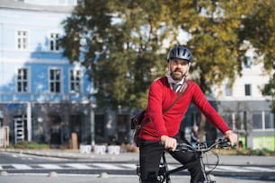 Hombre de negocios hipster viajero con bicicleta eléctrica que viaja al trabajo en la ciudad. Espacio de copia.