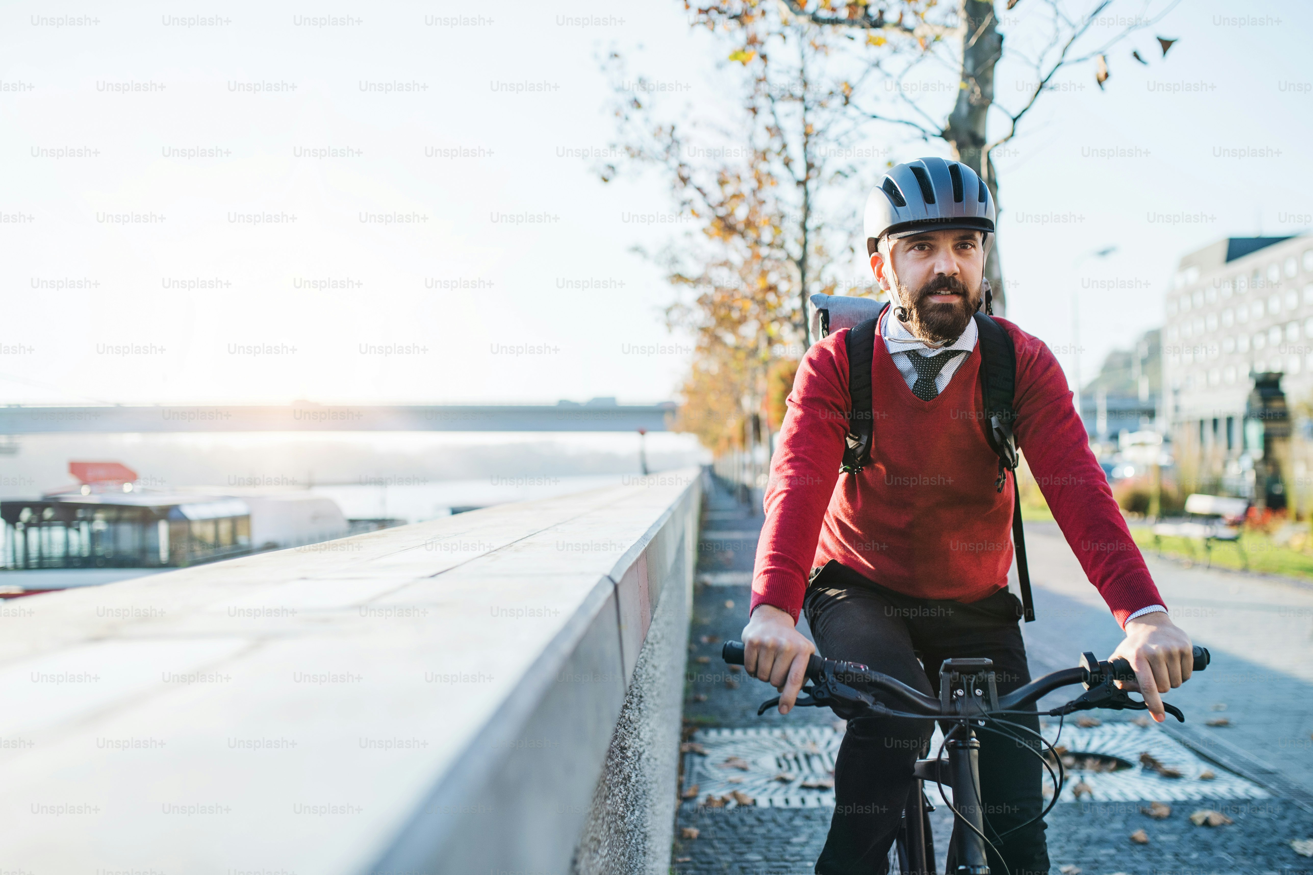 A front view of hipster businessman commuter with electric bicycle traveling to work in city. Copy space.