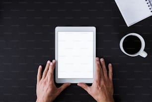 A top view of male hands holding tablet on a desk. A copy space.