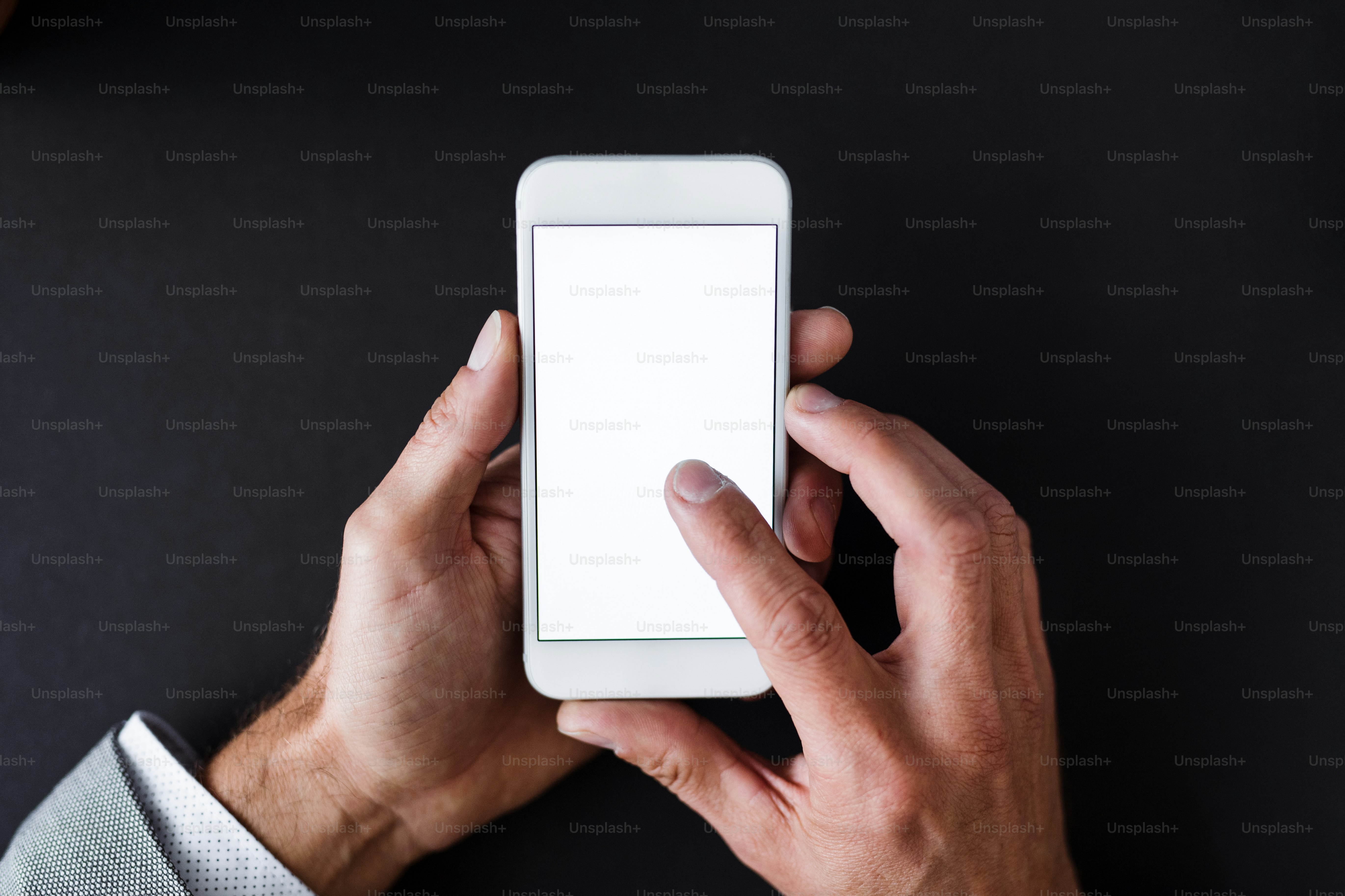 A top view of male hands holding smartphone on a desk. A copy space