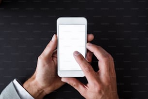 A top view of male hands holding smartphone on a desk. A copy space.