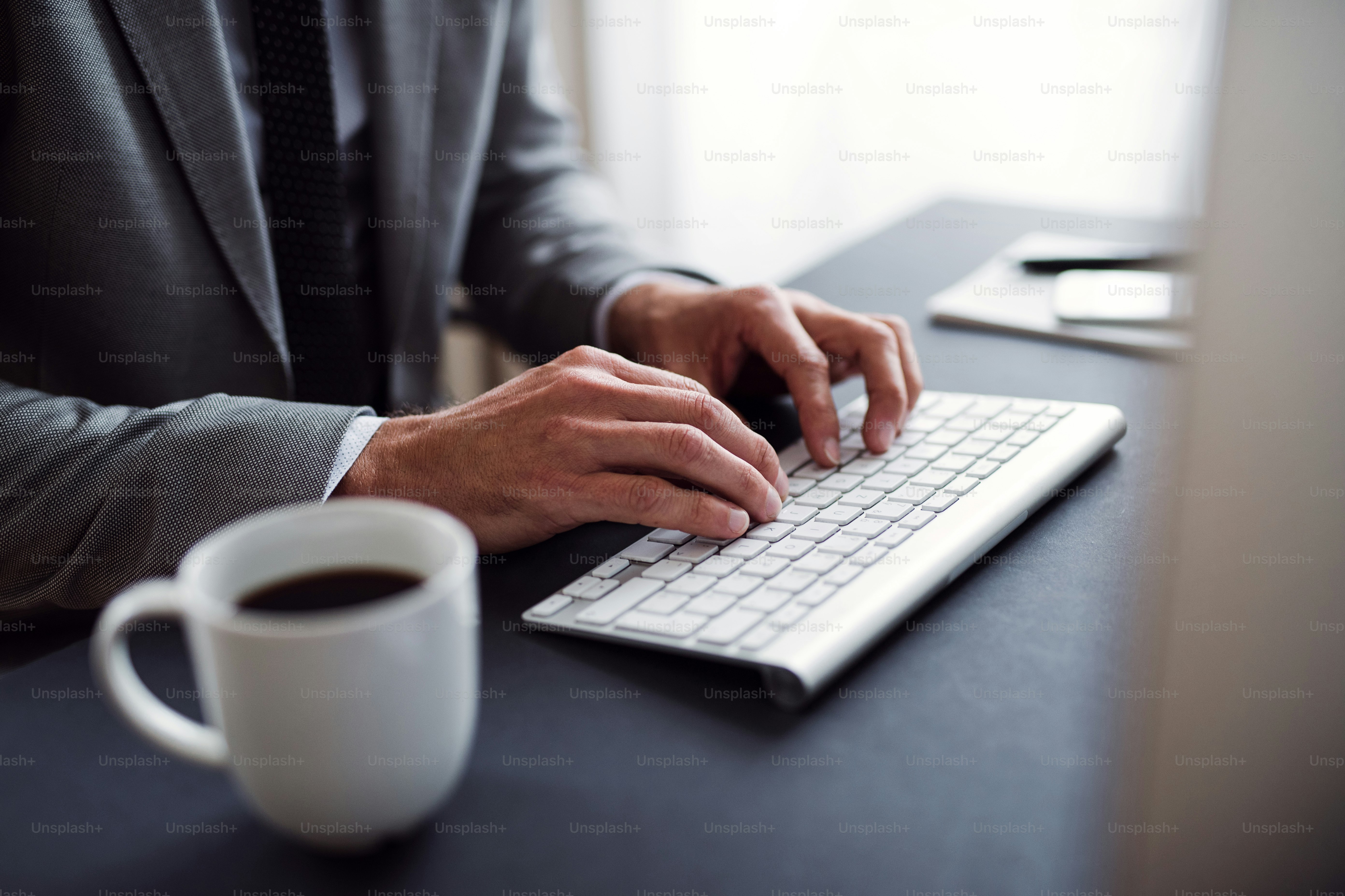 A midsection of businessman with laptop sitting at the desk in an ...