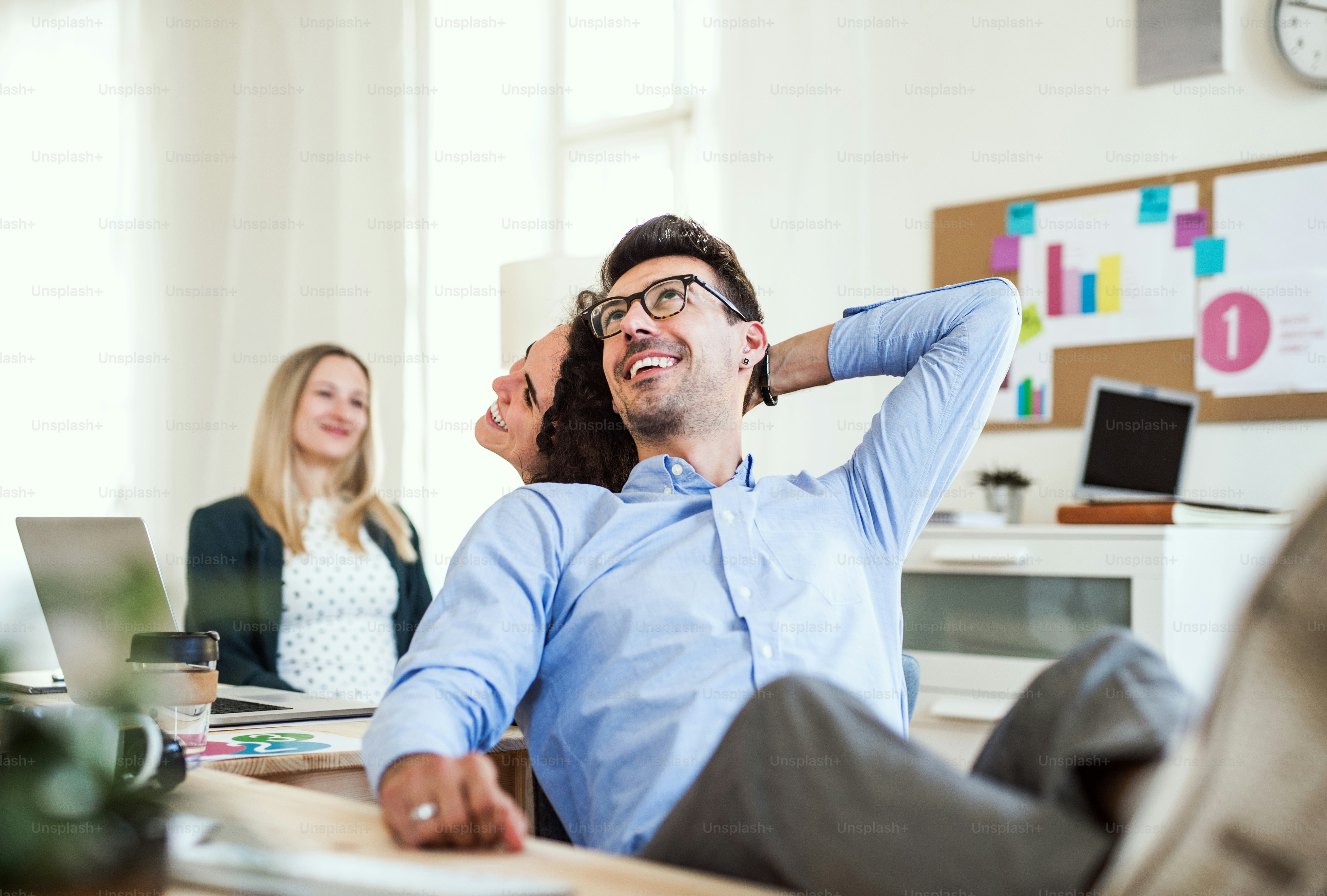 Groupe de jeunes hommes d’affaires joyeux, hommes et femmes, travaillant ensemble dans un bureau moderne.