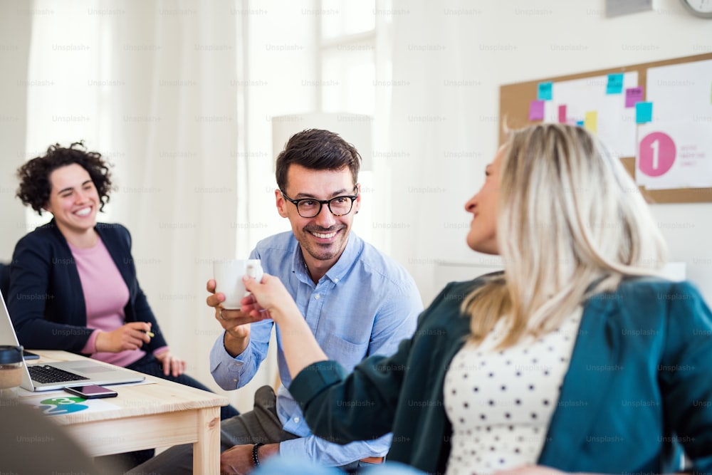 Group of young, cheerful, male and female businesspeople working together in a modern office.