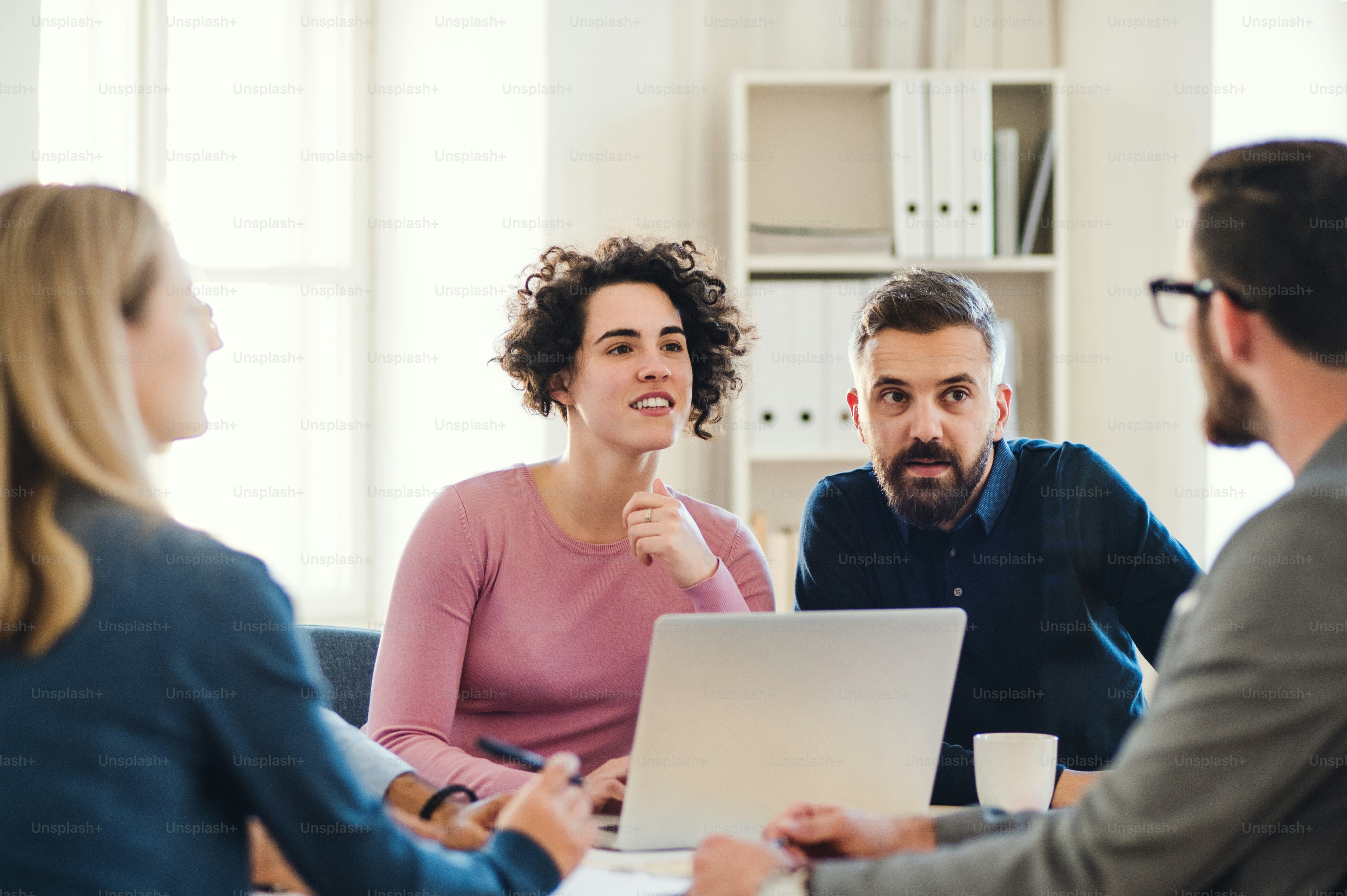 Group of young, cheerful, male and female businesspeople with laptop working together in a modern office