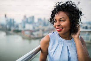 A close-up portrait of a black woman standing on a terrace in London. Copy space.