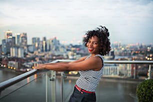 Un retrato de una mujer de negocios negra de pie frente al panorama de la vista de la azotea de Londres. Espacio de copia.
