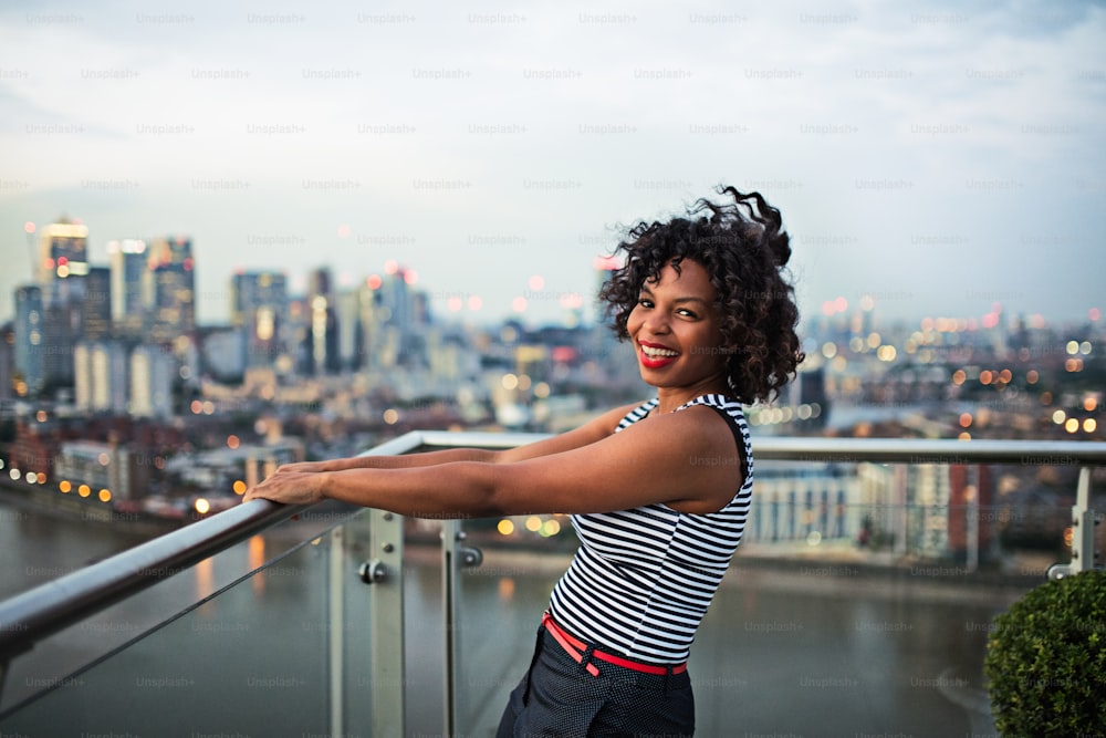 A portrait of black businesswoman standing against London rooftop view panorama. Copy space.