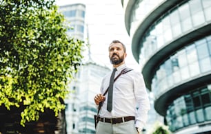 Hipster businessman walking outdoors on the street in London city. Copy space.