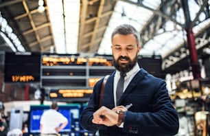 Businessman standing on the trian station in London, checking the time.