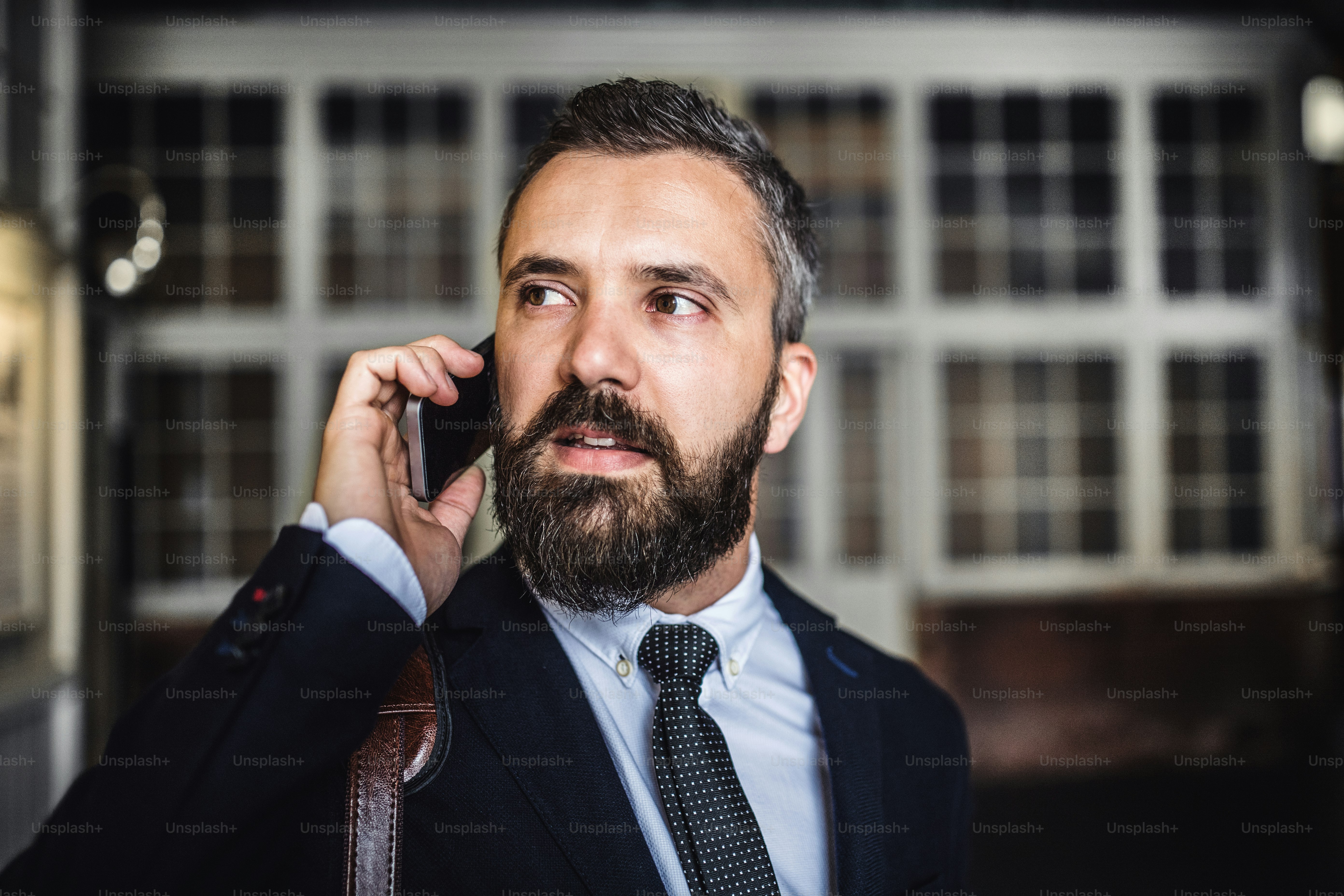 A close-up of hipster businessman with smartphone in the city, making a phone call. Copy space.