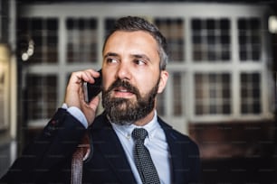 A close-up of hipster businessman with smartphone in the city, making a phone call. Copy space.