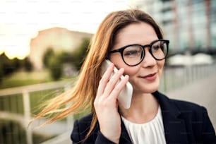 Gros plan d’une jeune femme d’affaires avec un smartphone à l’extérieur, passant un appel téléphonique.