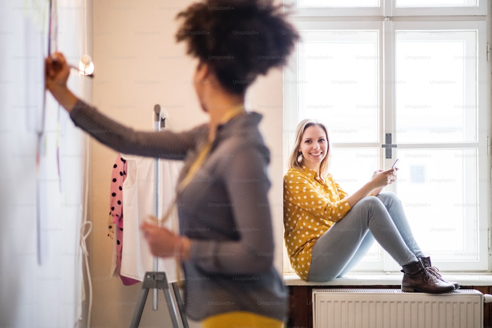 Young creative women with smartphone working in a studio, startup business.