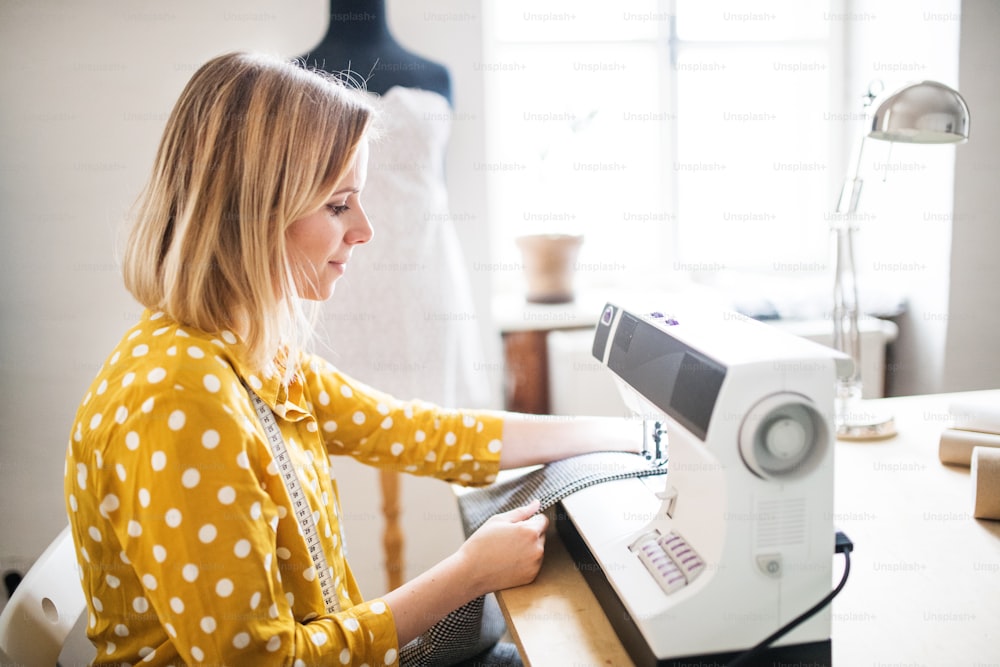 Young creative woman using sewing machine, startup business.
