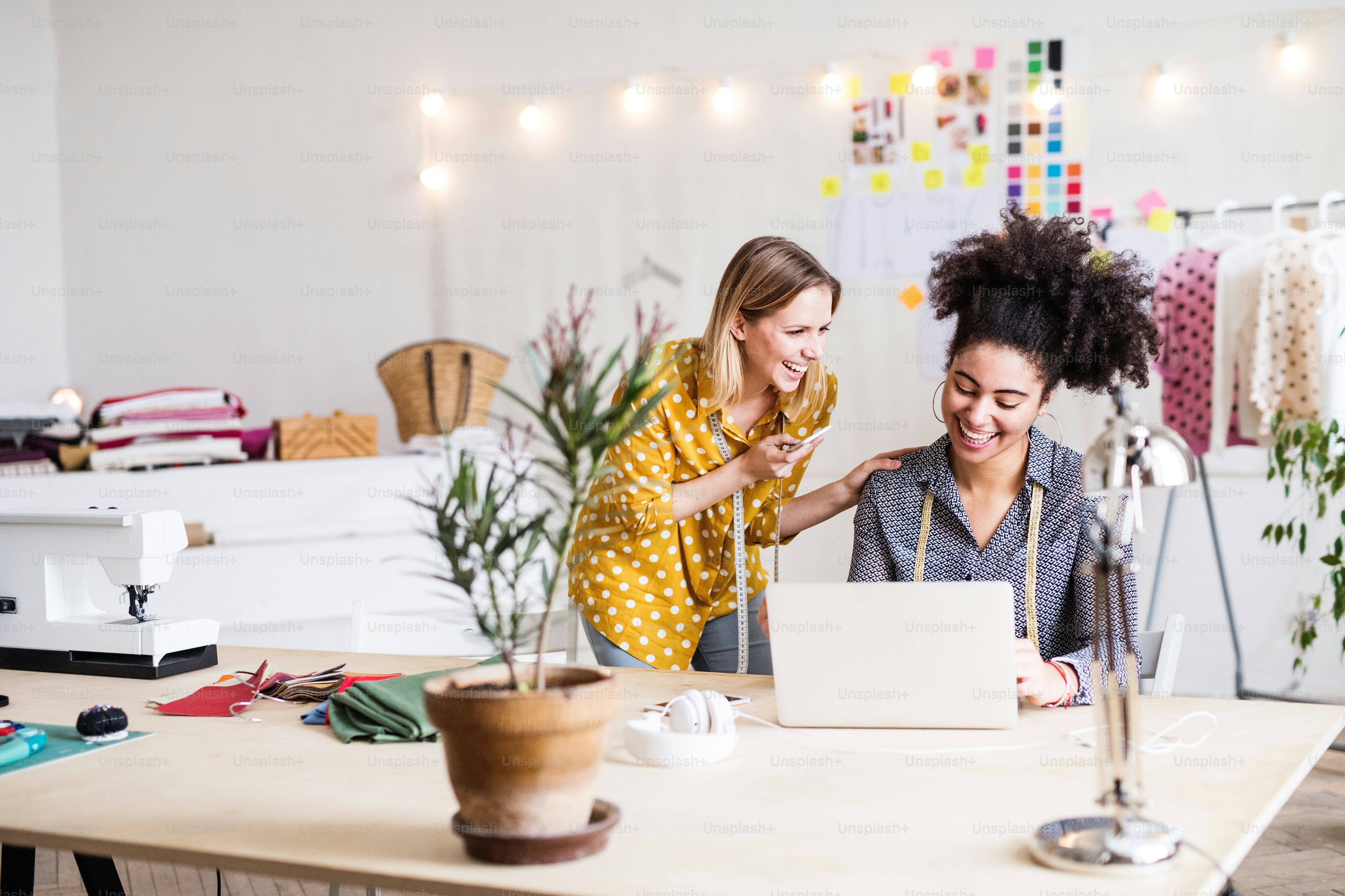 Wanita muda kreatif dengan laptop dan smartphone bekerja di studio, bisnis startup