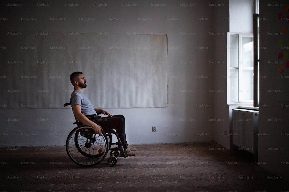Hnadsome man in wheelchair looking out of the window.