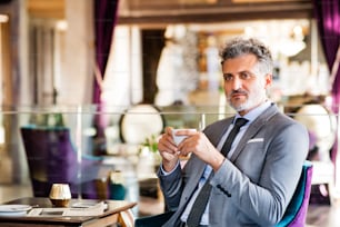 Mature businessman with coffee sitting in a hotel lounge.