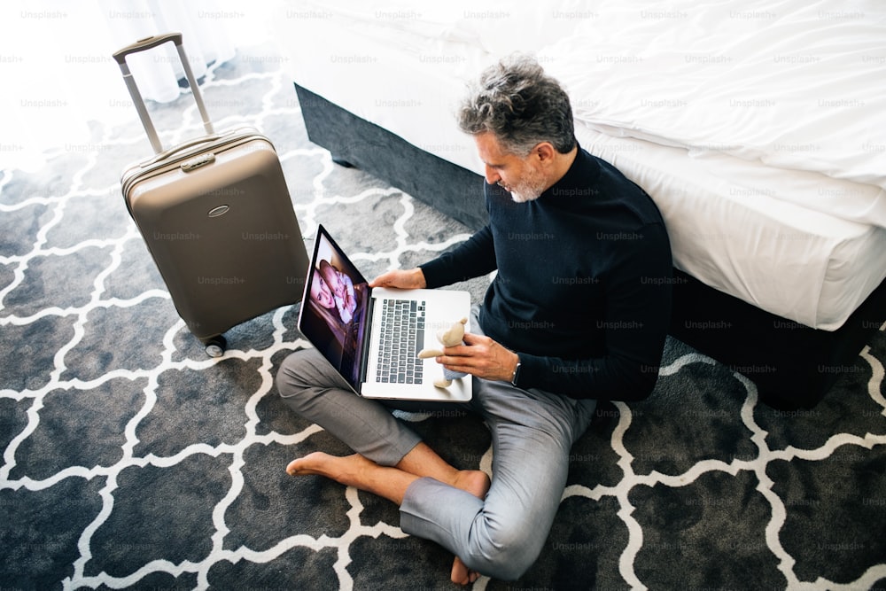 Unrecognizable businessman with laptop in a hotel room. Handsome man using online phone call and video.