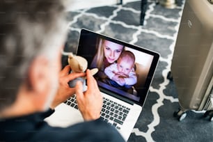 Unrecognizable businessman with laptop in a hotel room. Handsome man using online phone call and video.