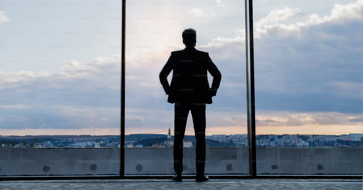 Mature businessman standing at the big windows in a hotel. Man looking ...