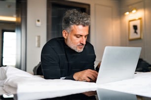 Mature businessman with laptop in a hotel room. Handsome man working on computer.