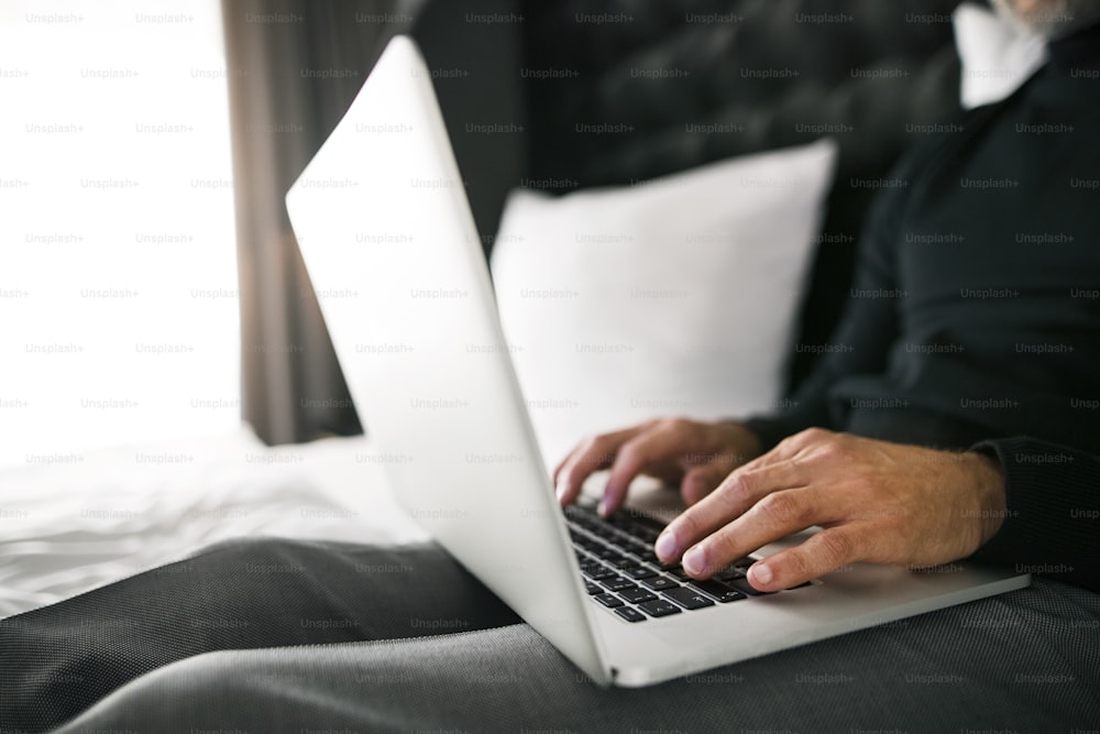Homme d’affaires méconnaissable avec un ordinateur portable dans une chambre d’hôtel. Bel homme travaillant sur ordinateur. Gros plan.