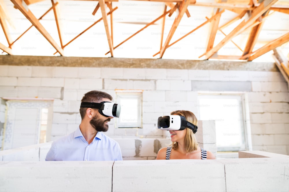 Giovane coppia sposata o architetti con occhiali per la realtà virtuale in cantiere.