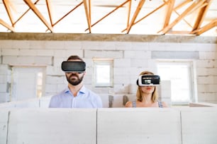 Jovem casal ou arquitetos com óculos de realidade virtual no canteiro de obras.