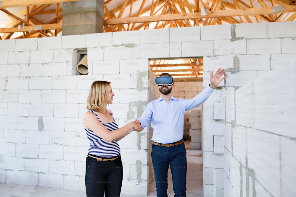 Young married couple or architects with virtual reality goggles at the construction site.