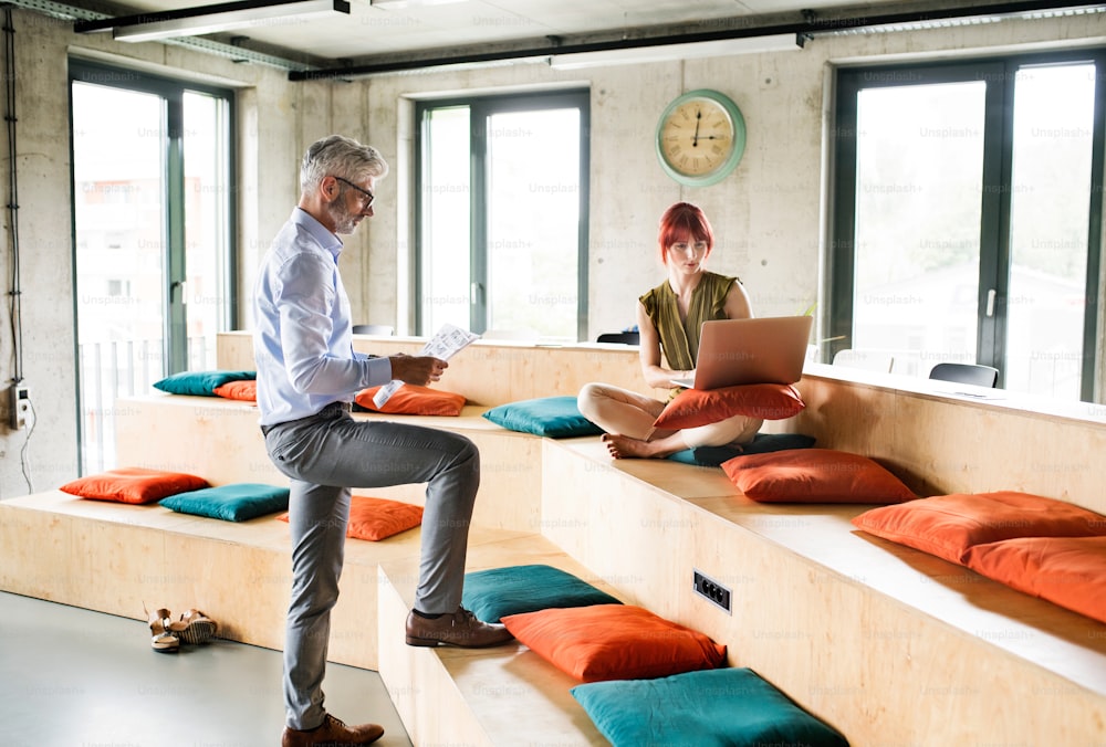 Two business people in workplace. Woman and man in creative office consulting a project together.