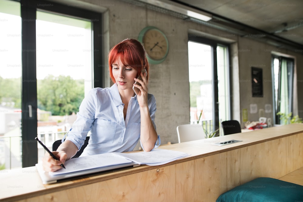 Beautiful businesswoman with smartphone in her office.