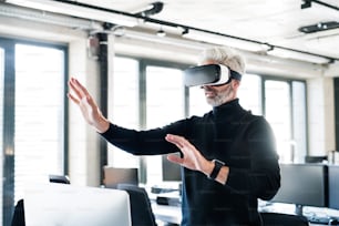 Handsome mature businessman with virtual reality goggles in the office.