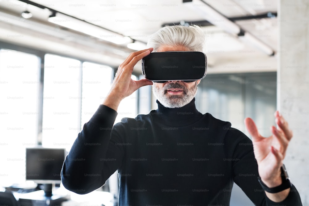 Guapo hombre de negocios maduro con gafas de realidad virtual en la oficina.