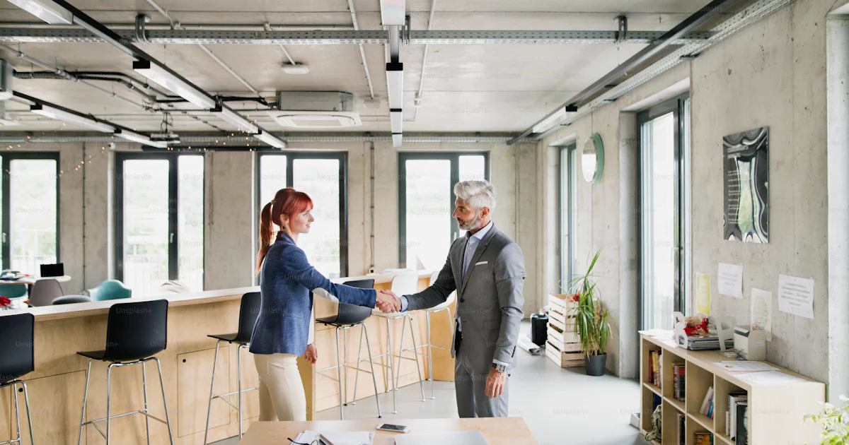 Zwei Geschäftsleute am Arbeitsplatz. Frau und Mann schütteln sich die ...