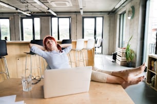 Schöne Geschäftsfrau mit Laptop im Büro mit den Füßen auf dem Schreibtisch.