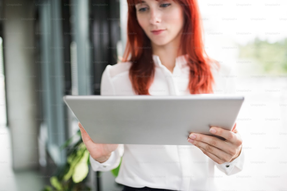 Hermosa joven empresaria con tableta en su oficina trabajando.