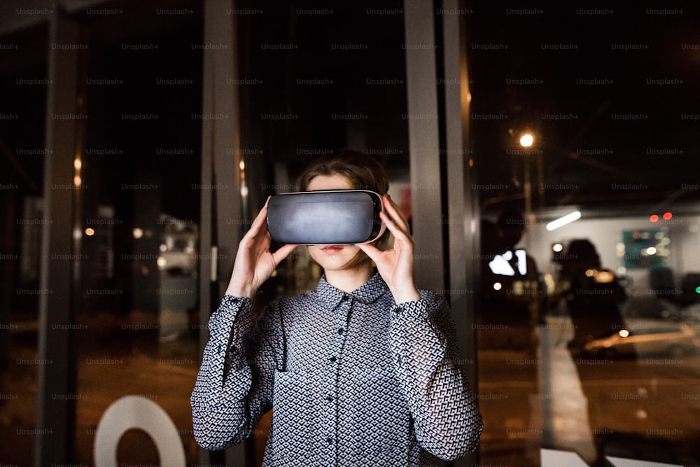 Young businesswoman in the office wearing virtual reality goggles.