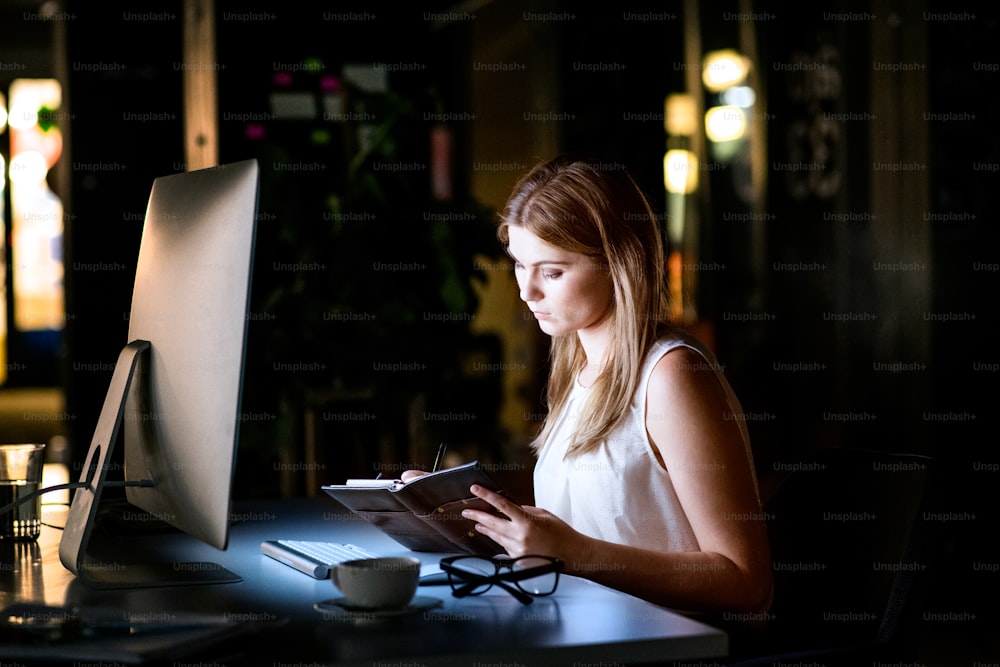 Beautiful young businesswoman in the office at night working late.