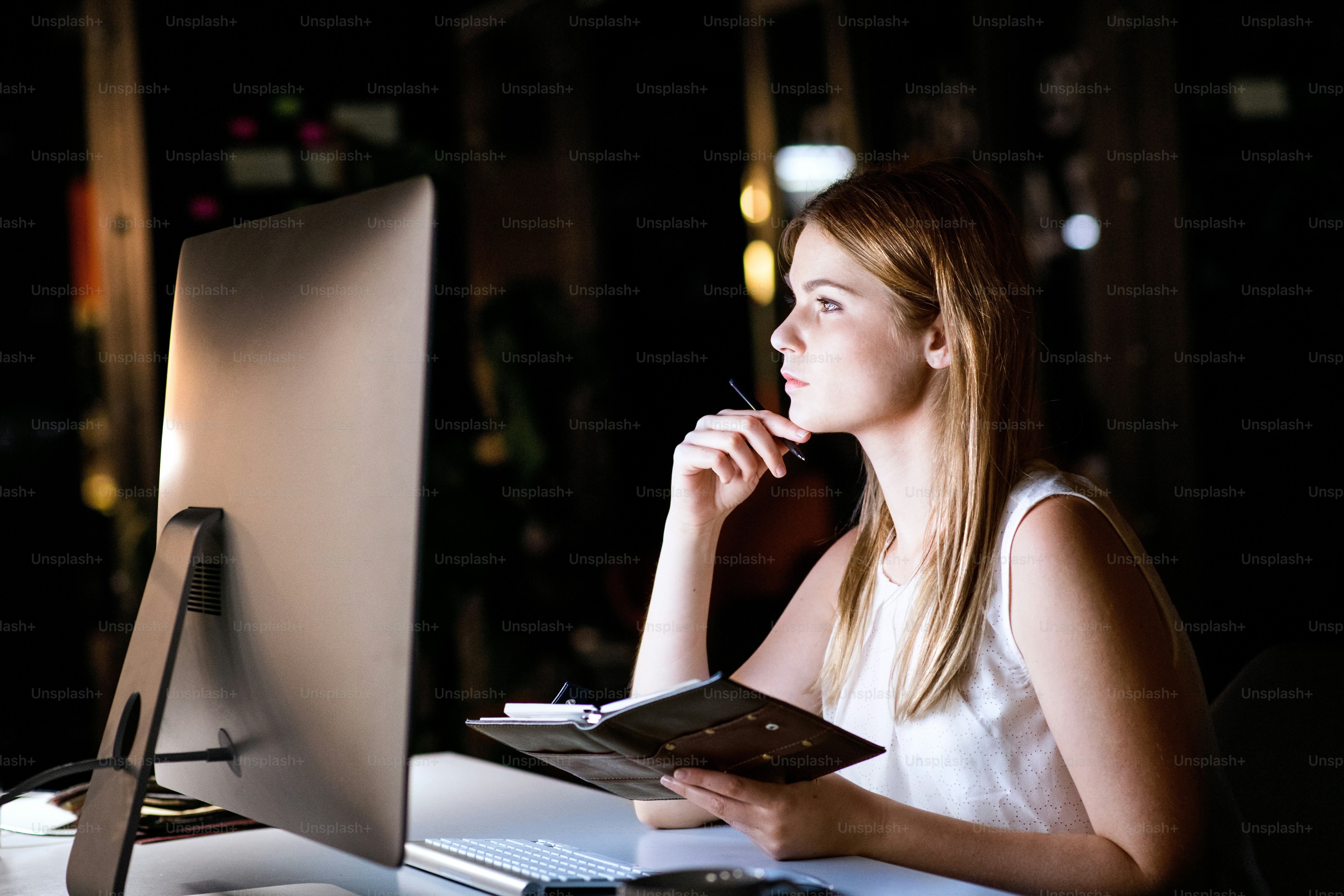 Beautiful young businesswoman in the office at night working late.