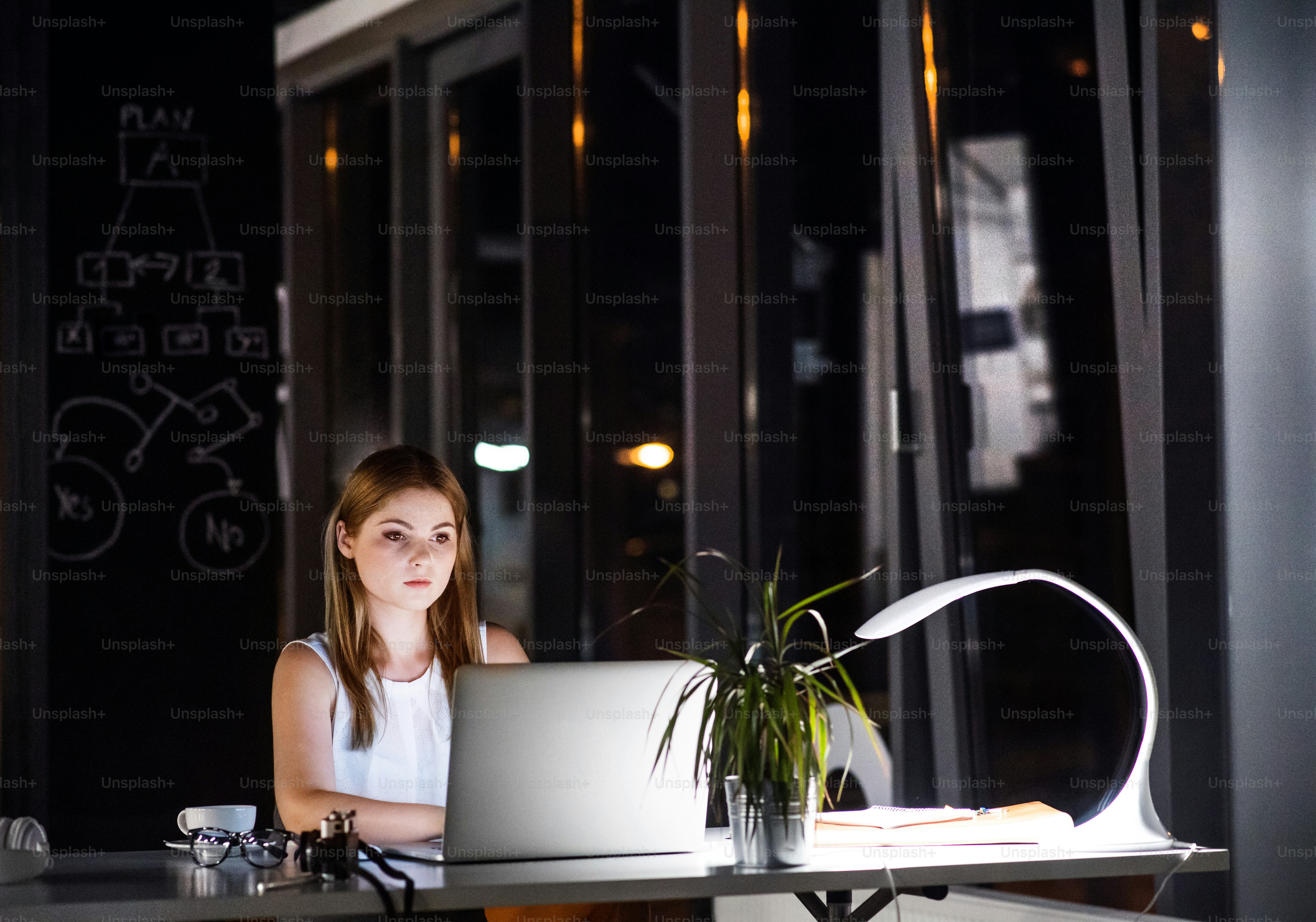 Beautiful young businesswoman in the office at night working late.