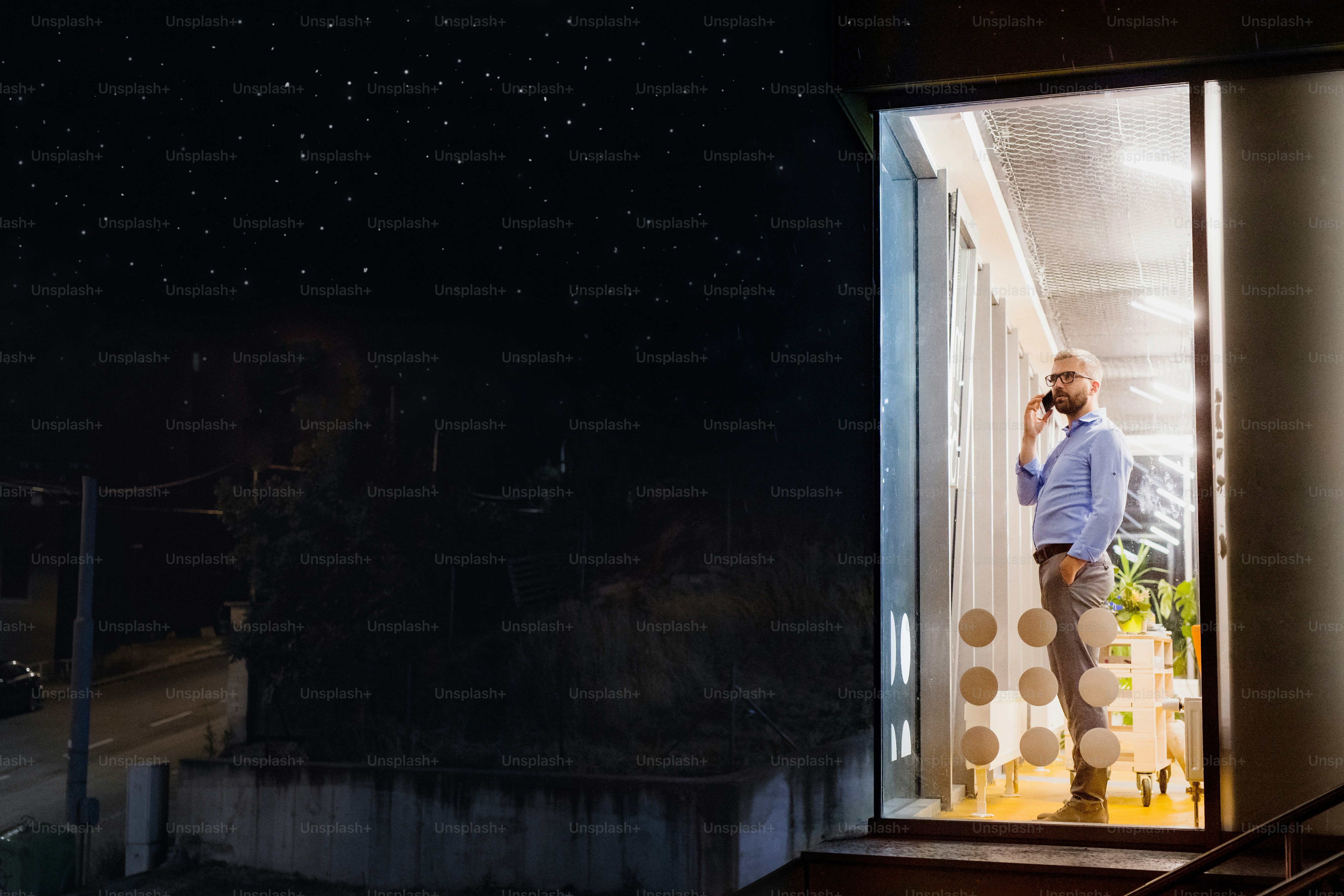 Hipster businessman with smart phone in his office working late at night.