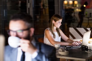 Two young businesspeople in the office at night working late.