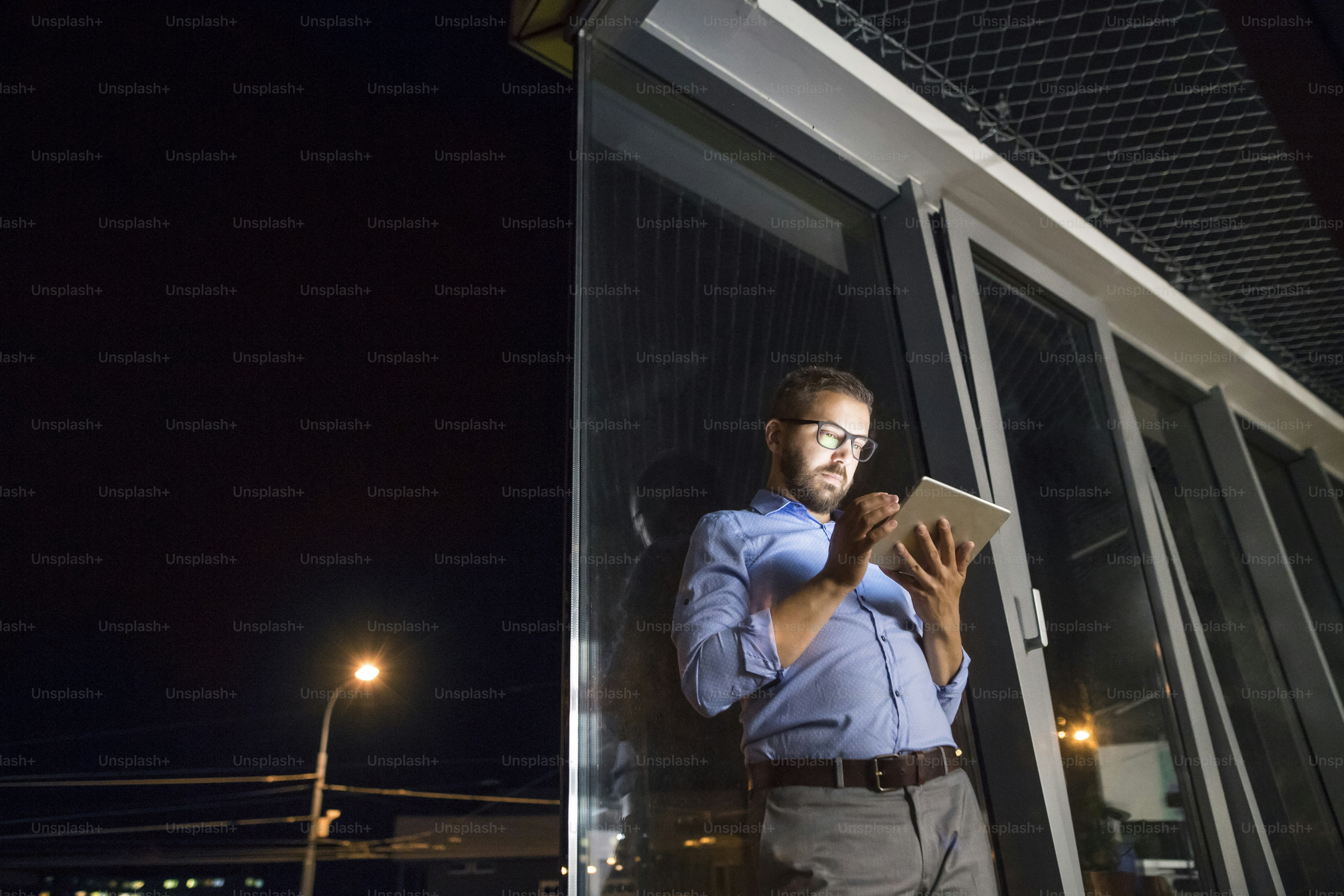 Thoughtful hipster businessman with tablet in his office working late at night.