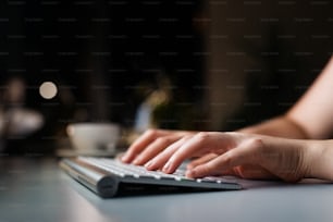 Nahaufnahme der Hände einer jungen Geschäftsfrau auf Computertastatur in ihrem Büro spät in der Nacht.