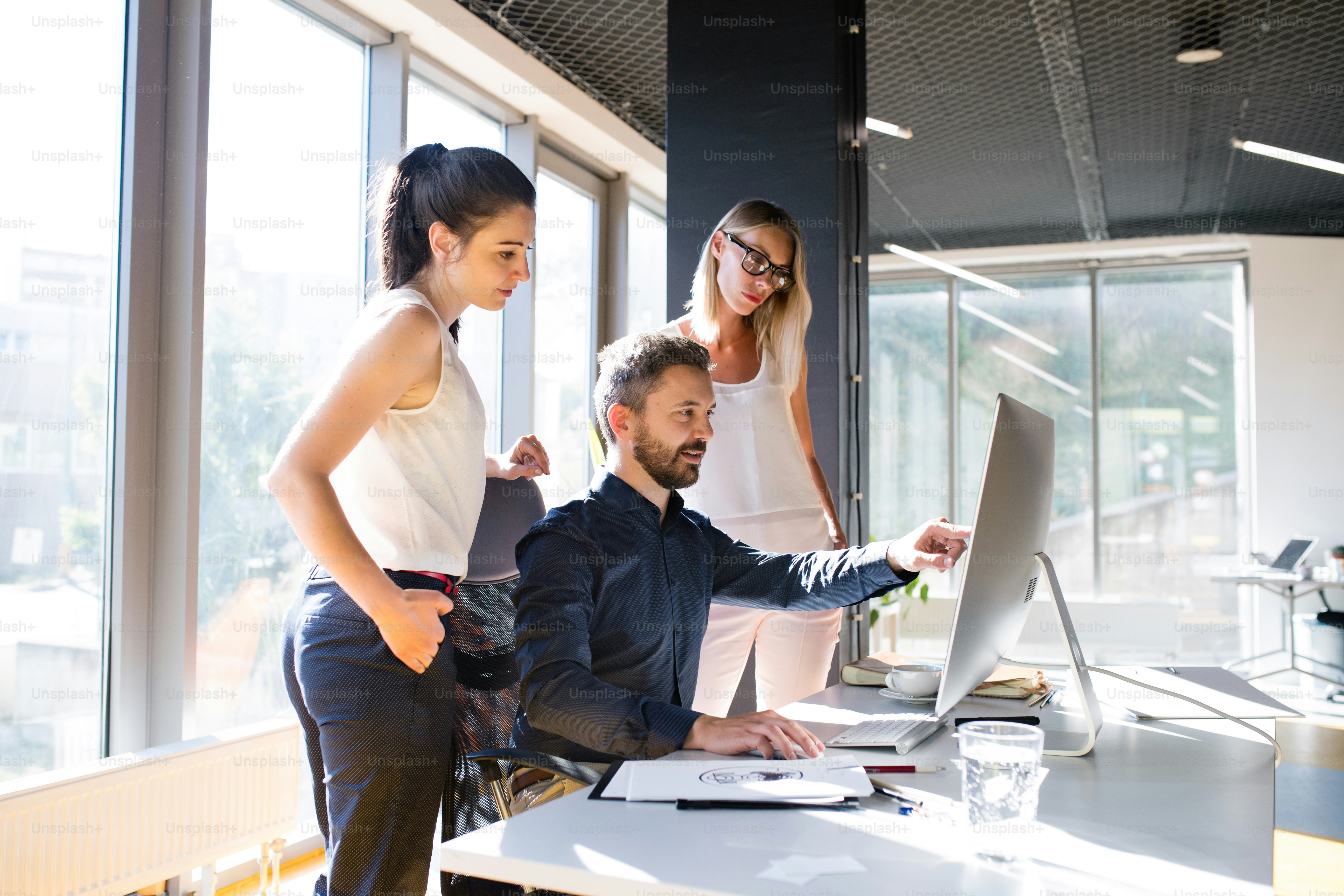 Three business people discussing in the workplace. Two women and man in the office working together