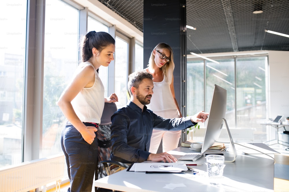 Three business people discussing in the workplace. Two women and man in the office working together.