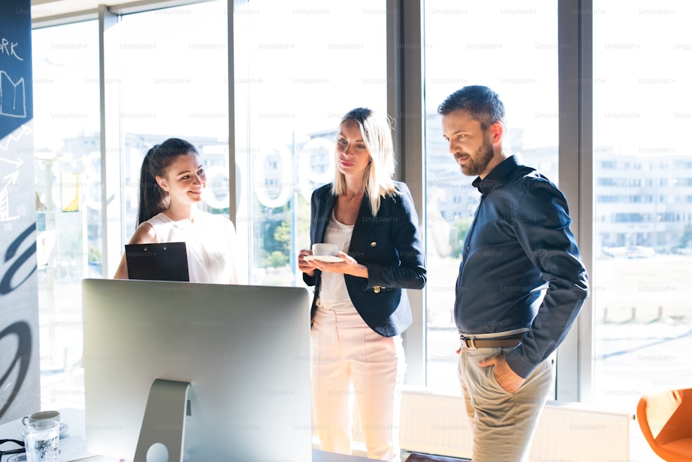 Tre uomini d'affari sul posto di lavoro che lavorano insieme. Due donne e un uomo discutono di un progetto.