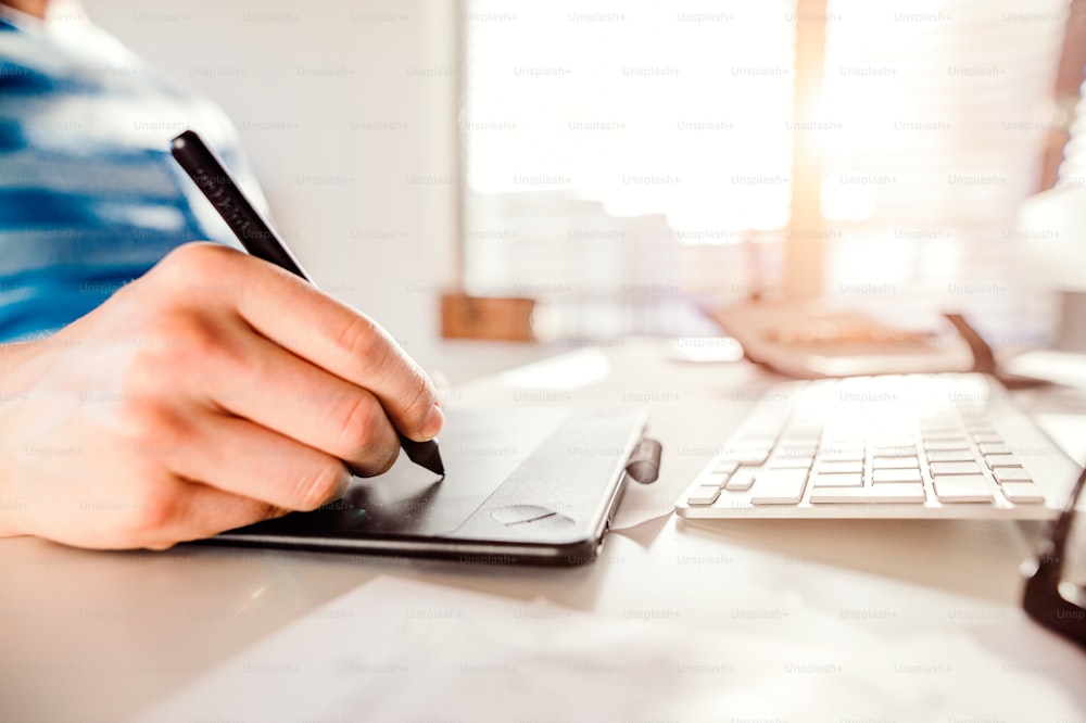 Hand of unrecognizable man working from home writing on graphic tablet